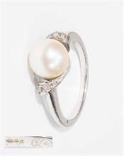 Damenring mit weißer Akoya-Perle, flankiert von kleinen Diamanten.