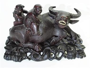 Liegender Büffel mit zwei Hirten auf dem Rücken.